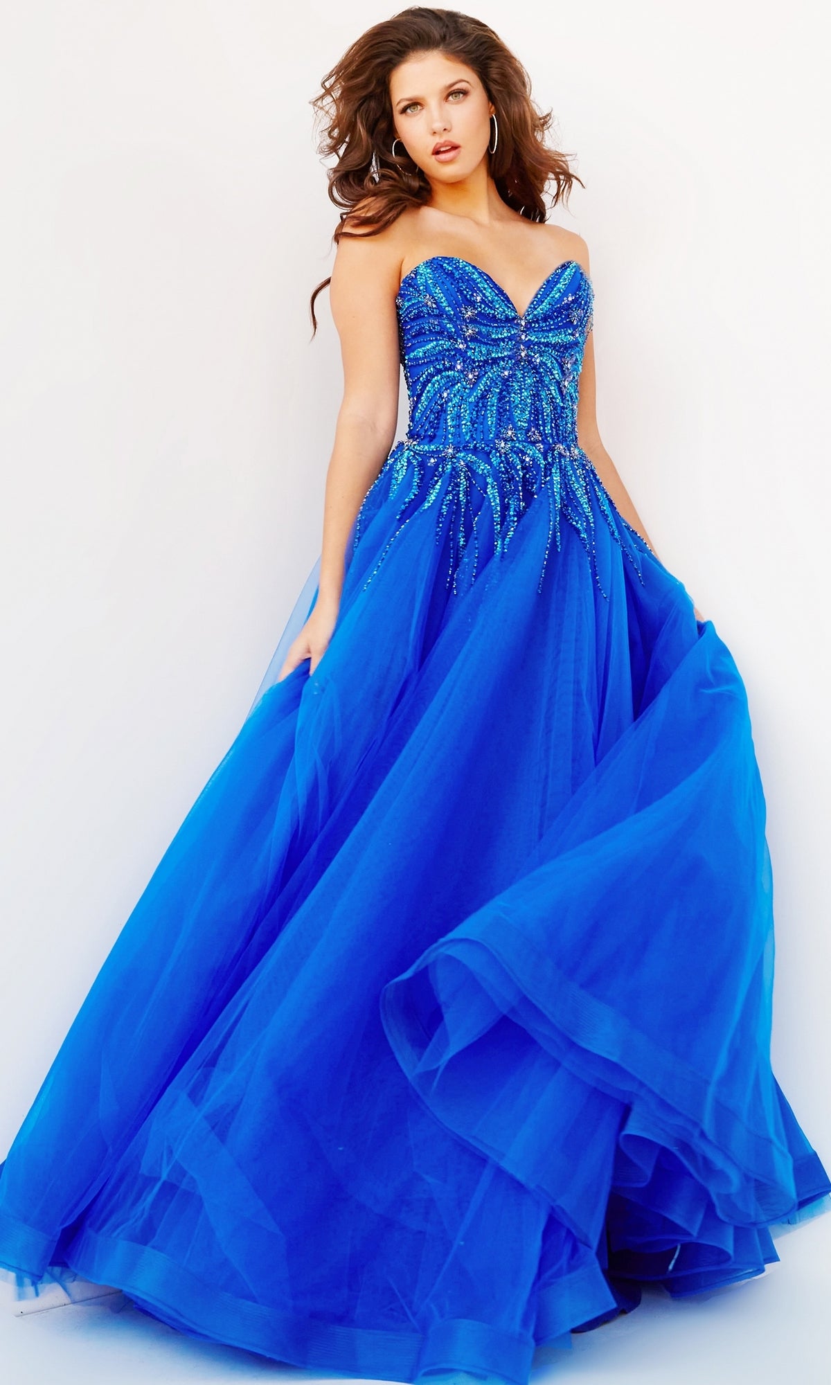 A woman poses in the royal blue Jovani Strapless Sweetheart Long Prom Gown 07946, featuring a beaded bodice and full tulle skirt, against a plain white background.